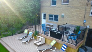 Une terrasse avec des chaises longues, une table et des chaises.