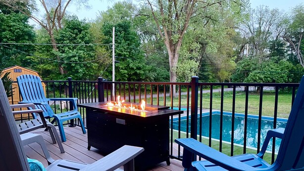 Une terrasse avec coin salon extérieur et foyer, donnant sur une piscine.