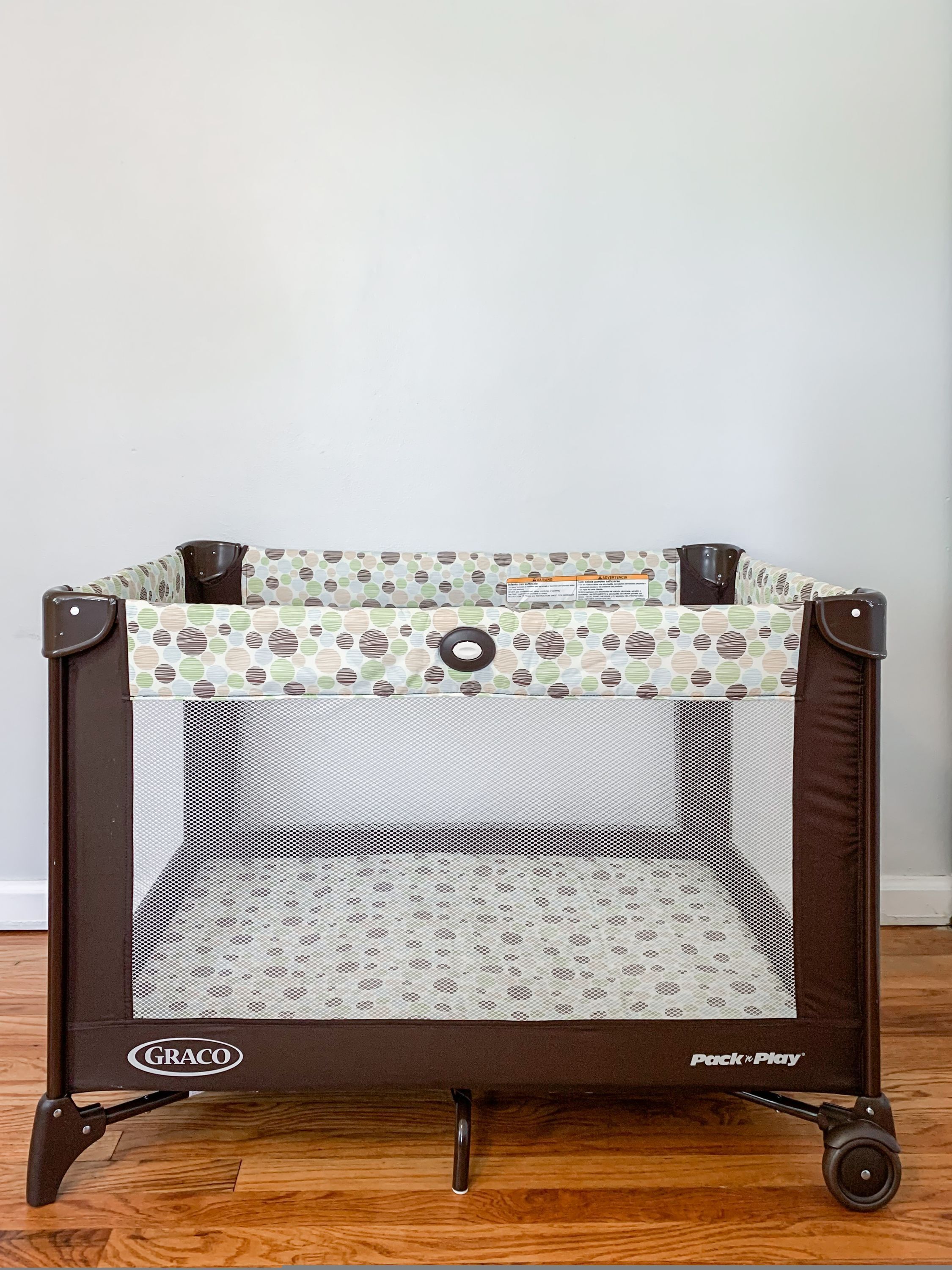 A portable crib with a polka dot pattern, labeled 'Pack n Play' and 'Graco'.