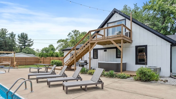 Een modern huis met een zwembad, een terras en een houten trap.