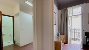 A spacious living area with a wooden floor, a wooden cabinet, and a large window with curtains. - La Platea de Bs As [7A] Views of the Libertad Palace (Buenos Aires)