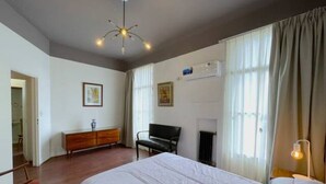 A hotel room with a large bed, a desk, a chair, and a radiator. - La Platea de Bs As [7A] Views of the Libertad Palace (Buenos Aires)