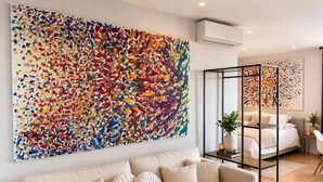 Ein modernes Wohnzimmer mit einem großen abstrakten Gemälde, einer Couch und einer Glastrennwand.