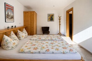 Une chambre à coucher avec un lit, des oreillers, une chaise, un porte-manteau et deux affiches au mur.