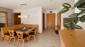 Un comedor con una mesa y sillas de madera, una lámpara colgante y una puerta al fondo.
