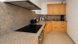 Cocina compacta con encimeras de granito, estufa, cafetera y armarios de madera.