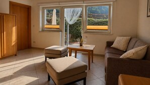Una habitación con sofá, reposapiés, mesa y vistas amplias a través de grandes ventanales.