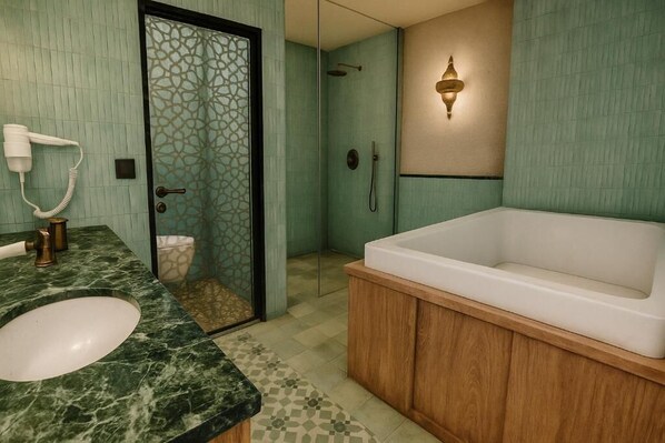 A bathroom with a marble sink, a freestanding bathtub, a glass-enclosed shower, and a wall-mounted light fixture.