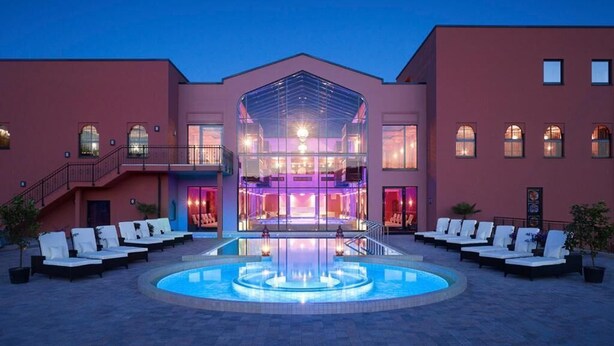 A hotel with a central pool, lounge chairs, and a glass-enclosed spa area. - Le Marrakech Boutique Hotel (Kleinblittersdorf)