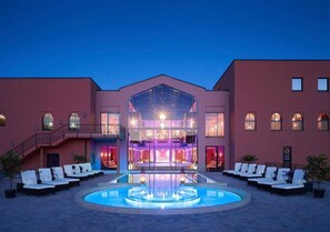 A hotel with a central pool, lounge chairs, and a glass-enclosed spa area. - Le Marrakech Boutique Hotel  (Kleinblittersdorf)
