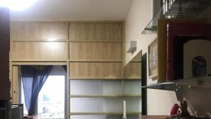 Ein kompakter Wohnraum mit Küchenzeile, einer Couch und einem Fenster mit Vorhängen.