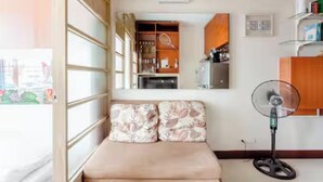 Ein Schlafzimmer mit Bett, Nachttisch, Spiegel, Kleiderschrank und Ventilator.