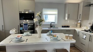 Een moderne keuken met een centraal eiland, roestvrijstalen apparatuur en houten krukken.