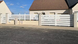 Il s’agit d’une propriété résidentielle fermée, dotée d’une façade en briques, d’un toit en pente et d’une clôture blanche en bois.