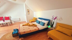 Une chambre à coucher avec un lit, un canapé, une petite table et une plante en pot.