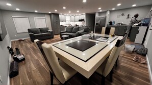 Eine moderne Küche mit integrierten Geräten, ein Essbereich mit Glastisch und ein Wohnbereich mit Sofas.