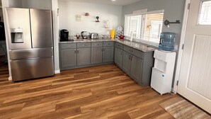 Eine moderne Küche mit grauen Schränken, Edelstahlgeräten und Holzboden.