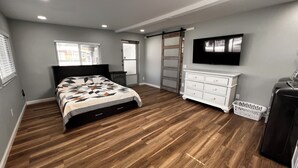 Ein Schlafzimmer mit Bett, Schminktisch, Fernseher und Schiebetürenschrank.