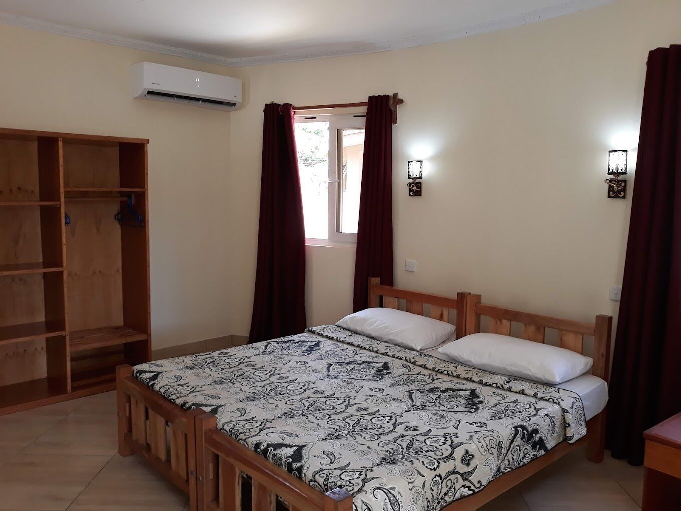 A bedroom with a wooden bed, a wardrobe, and an air conditioning unit.