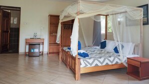 A bedroom with a four-poster bed, a wooden desk, and a wardrobe. - Likizo Cottages & Resort Kanamai (Mtwapa)