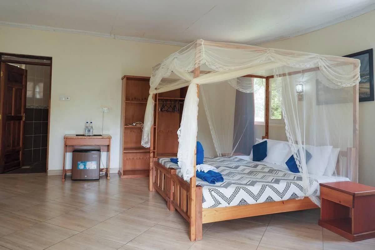 A bedroom with a four-poster bed, a wooden desk, and a wardrobe.