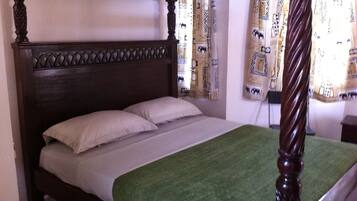 A four-poster bed with a dark wooden headboard and a green throw blanket.