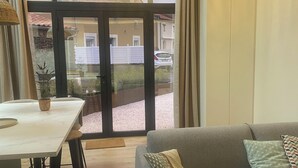 Un salon moderne comprenant un canapé, une table à manger et une grande fenêtre donnant sur la rue et les bâtiments voisins.