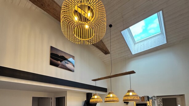 Une cuisine moderne dotée d’un îlot central, de luminaires suspendus et d’une verrière.