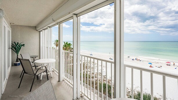Ein Balkon mit Blick auf einen Strand, einem Tisch mit Stühlen und einem Blumentopf.