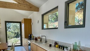 Uma cozinha moderna com armários de madeira, uma janela grande e um espaço de refeições com cadeiras.