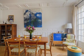Uma sala de jantar com uma mesa de madeira, cadeiras e um vaso de flores.