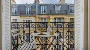 A balcony with a round table, a vase with flowers, and a croissant on a plate. - Paris sacré coeur prestige residence (Paris)