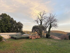 Ein Garten mit Schwimmbad, Sitzgelegenheiten im Freien und Blick auf Hügel.