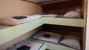 Kerrossängyllä varustettu huone, jossa on kolme kerrosta, ja jokaisessa kerroksessa on tyyny ja peitto.