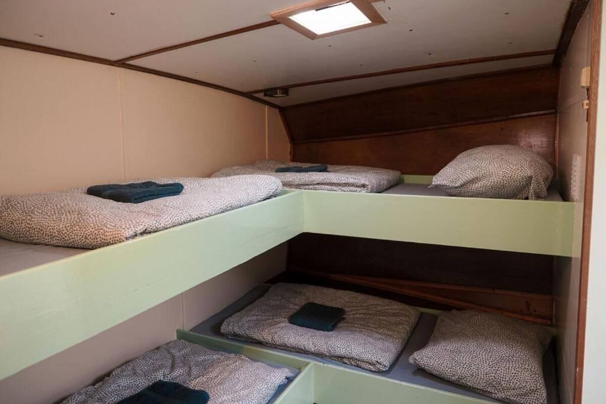 A bunk bed room with three levels, each with a pillow and a blanket.