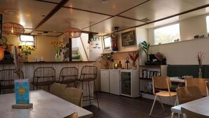 Tunnelmallinen ravintola, jossa on puuhuonekalut, baarialue ja kirjahylly.