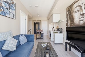A modern living room with a blue sofa, a coffee table, and a large painting on the wall.
