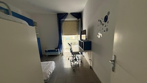 A hotel room with a bed, desk, chair, and a window with curtains. - Beachfront with ⛱️ umbrella included (Pescara)