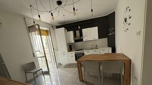 A modern kitchen with white cabinets, a wooden dining table, and a black backsplash. - Beachfront with ⛱️ umbrella included (Pescara)