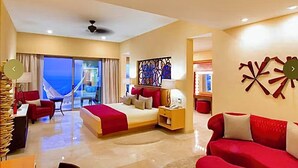 A spacious hotel room with a large bed, a red sofa, a desk, and a balcony with a view. - Magnificent Ocean view suite with private balcony jacuzzi (Puerto Vallarta)