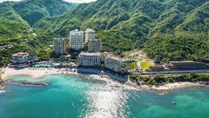 A resort with multiple high-rise buildings, a beach, and a mountainous backdrop. - Magnificent Ocean view suite with private balcony jacuzzi (Puerto Vallarta)