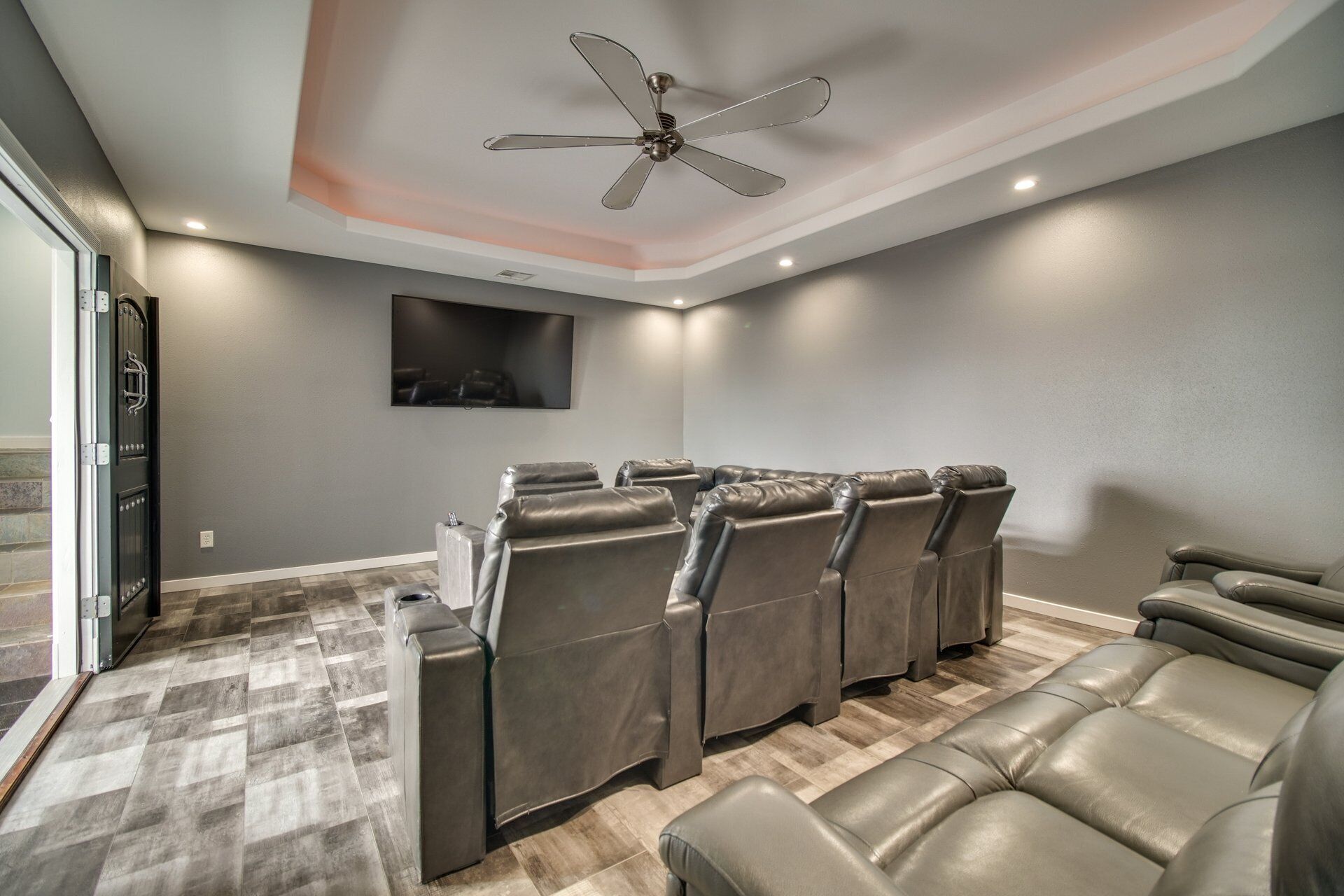 A home theater room with a ceiling fan, a large screen, and multiple leather recliner seats.