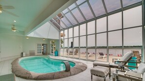 A large indoor swimming pool with a view of the water through large windows.