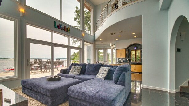 A spacious living room with a large sectional sofa, a dining area with a view of the water, and a kitchen with modern appliances.
