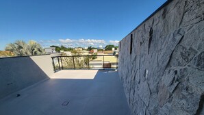 Une terrasse sur le toit, avec un mur en pierre et une vue sur les bâtiments et les arbres.