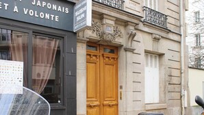 A building with a wooden door and a sign above it. - Timeless apartment in a Haussmannian building (Paris)