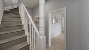 Un escalier avec des rampes blanches et un mur de couleur claire.