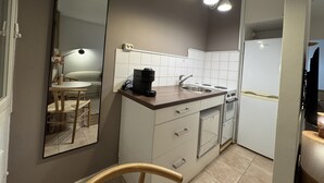 Eine kleine Küche mit Spüle, Herd und Kaffeemaschine auf der Arbeitsfläche.