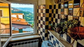 A room with a window overlooking a scenic view of a village and mountains. - Artist's Refuge (Cerri)