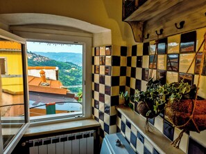 Ein Zimmer mit Fenster und Blick auf ein malerisches Dorf und Berge.